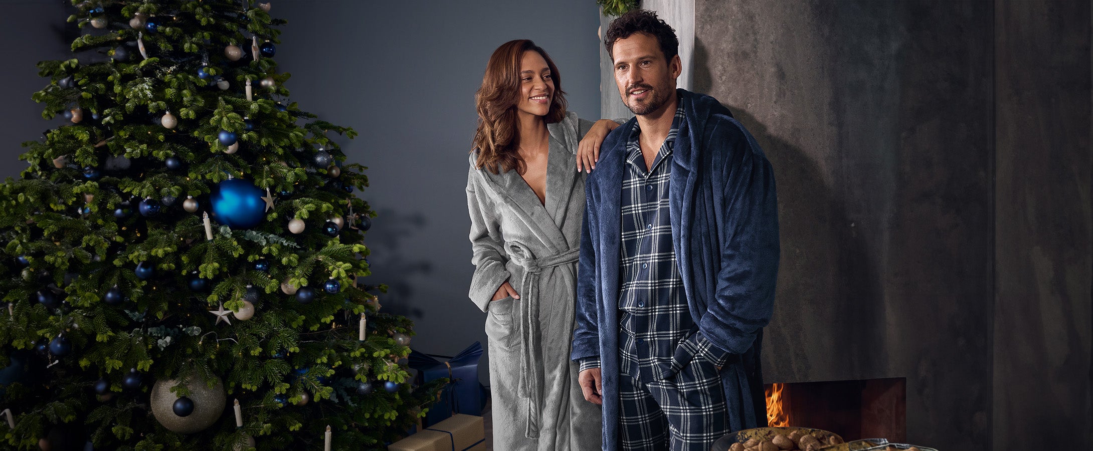 Woman and man wearing e.s. check pyjamas and e.s. bathrobes in a Christmas living room