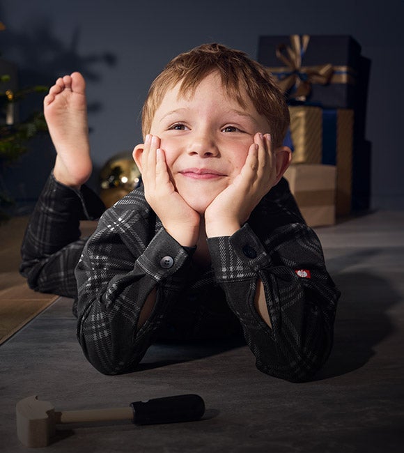 A boy wearing the e.s. check pyjama in a Christmas living room
